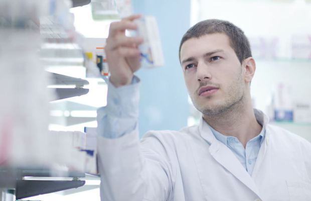 young male doctor looking at pill packet