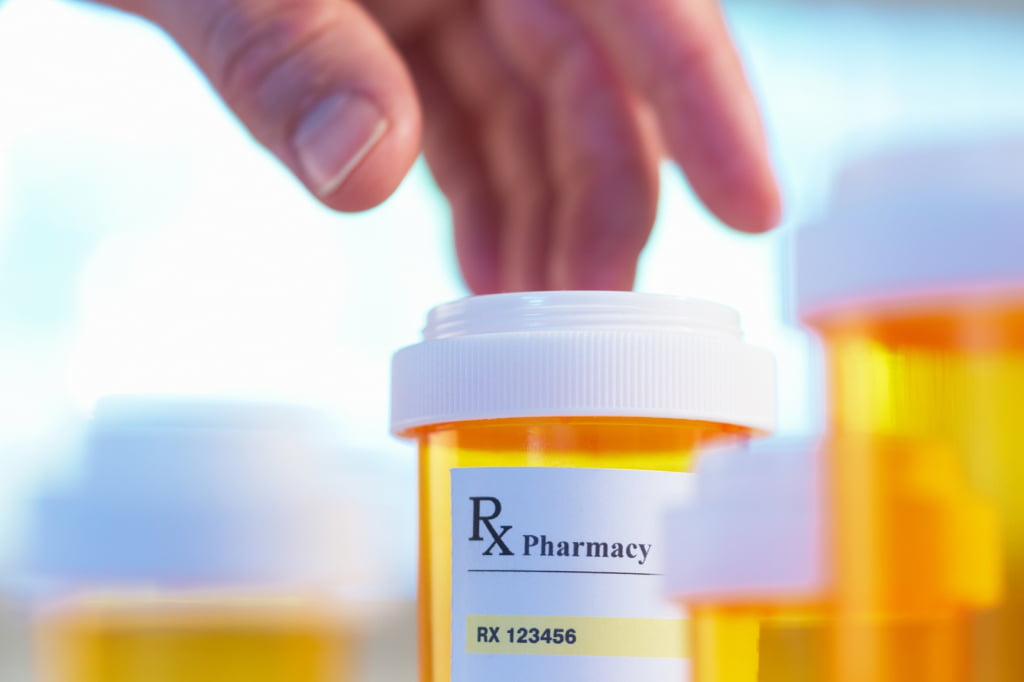 person picking out a bottle of pills
