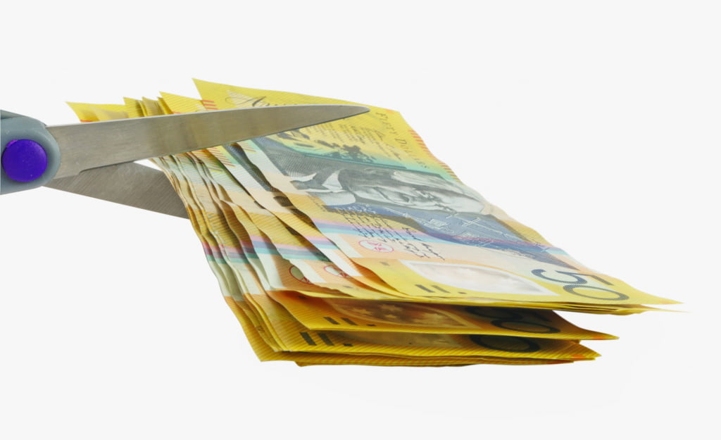 scissors cutting many 50 dollar notes
