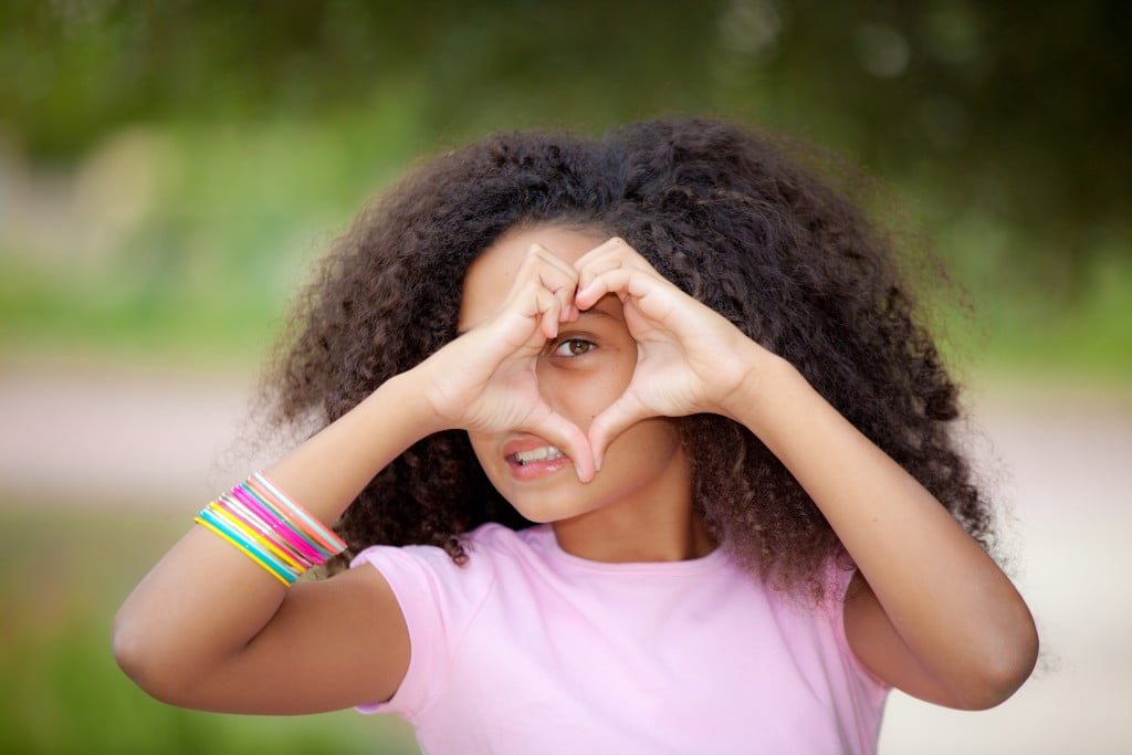 heartkids: teenage girl makes heart shape with hands over her eye