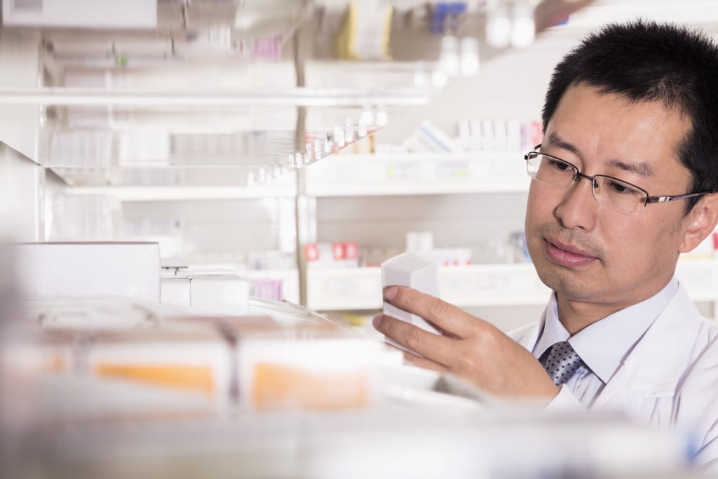 male pharmacist looking at pills