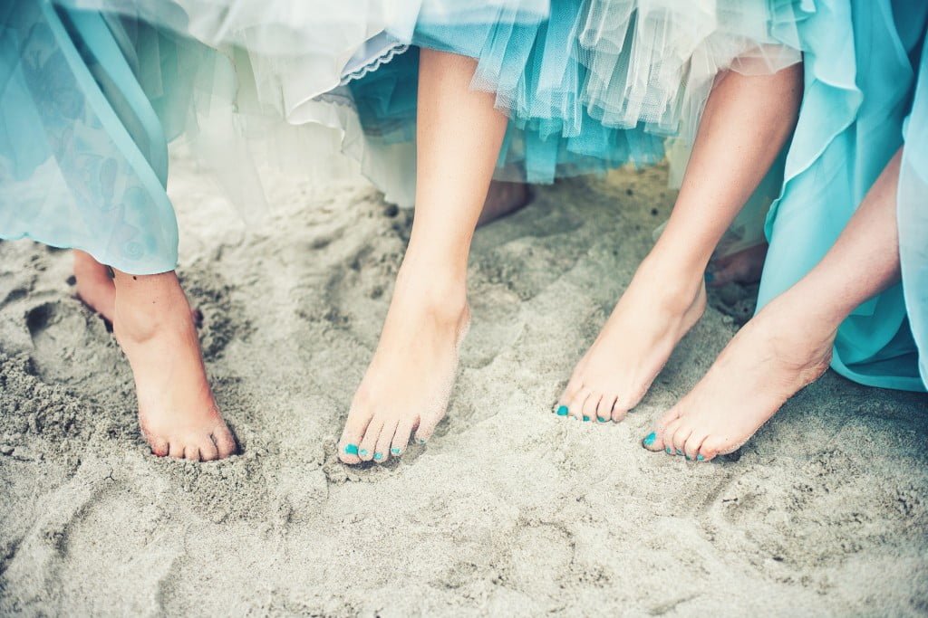 ovarian cancer symptoms: women in teal dresses at beach with teal toenail polish