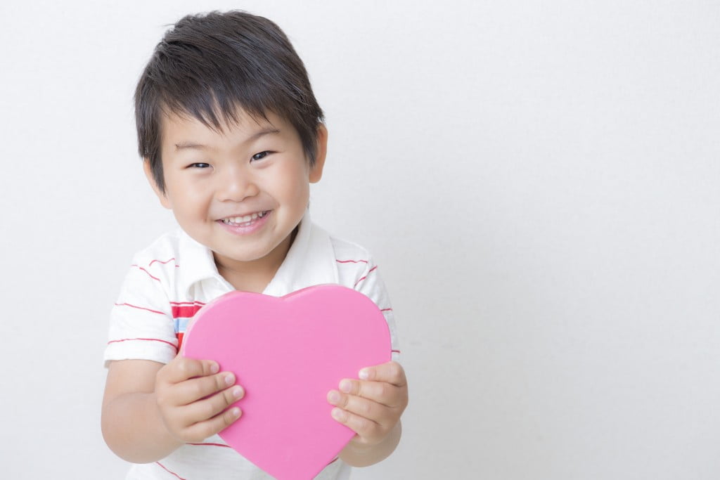 Congenital heart disease: little boy holding pink cardboard heart