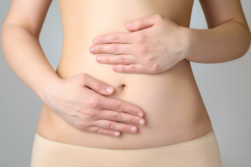 endometriosis concept: woman holds hands to belly