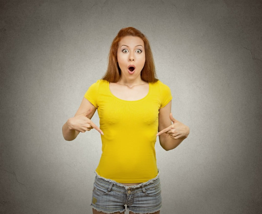 endometriosis concept: woman in yellow t-shirt points to her belly