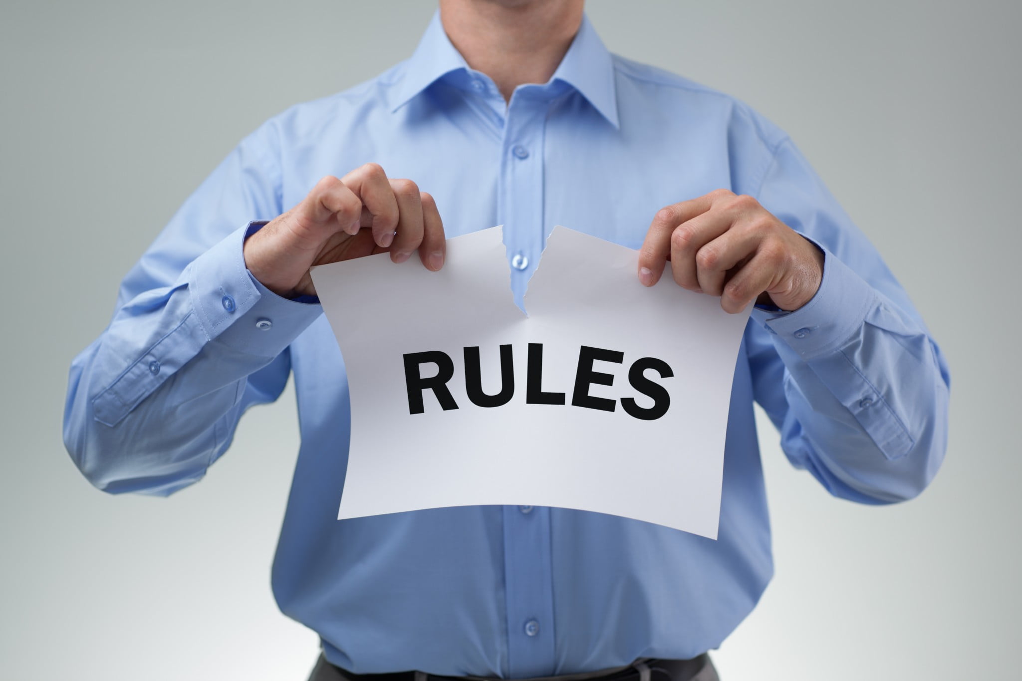 Man tears up page that reads "rules" (Harper Review)