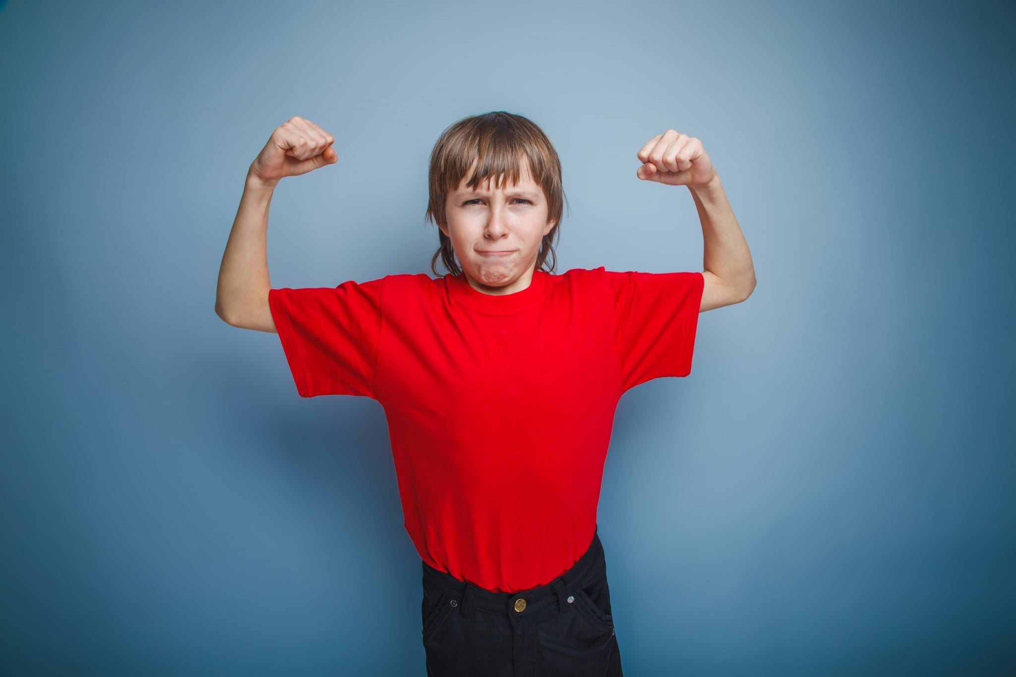 Boys and body image: young boy flexes skinny biceps