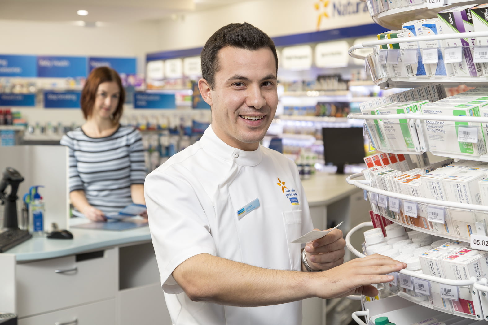 Pharmacist in foreground of dispensary