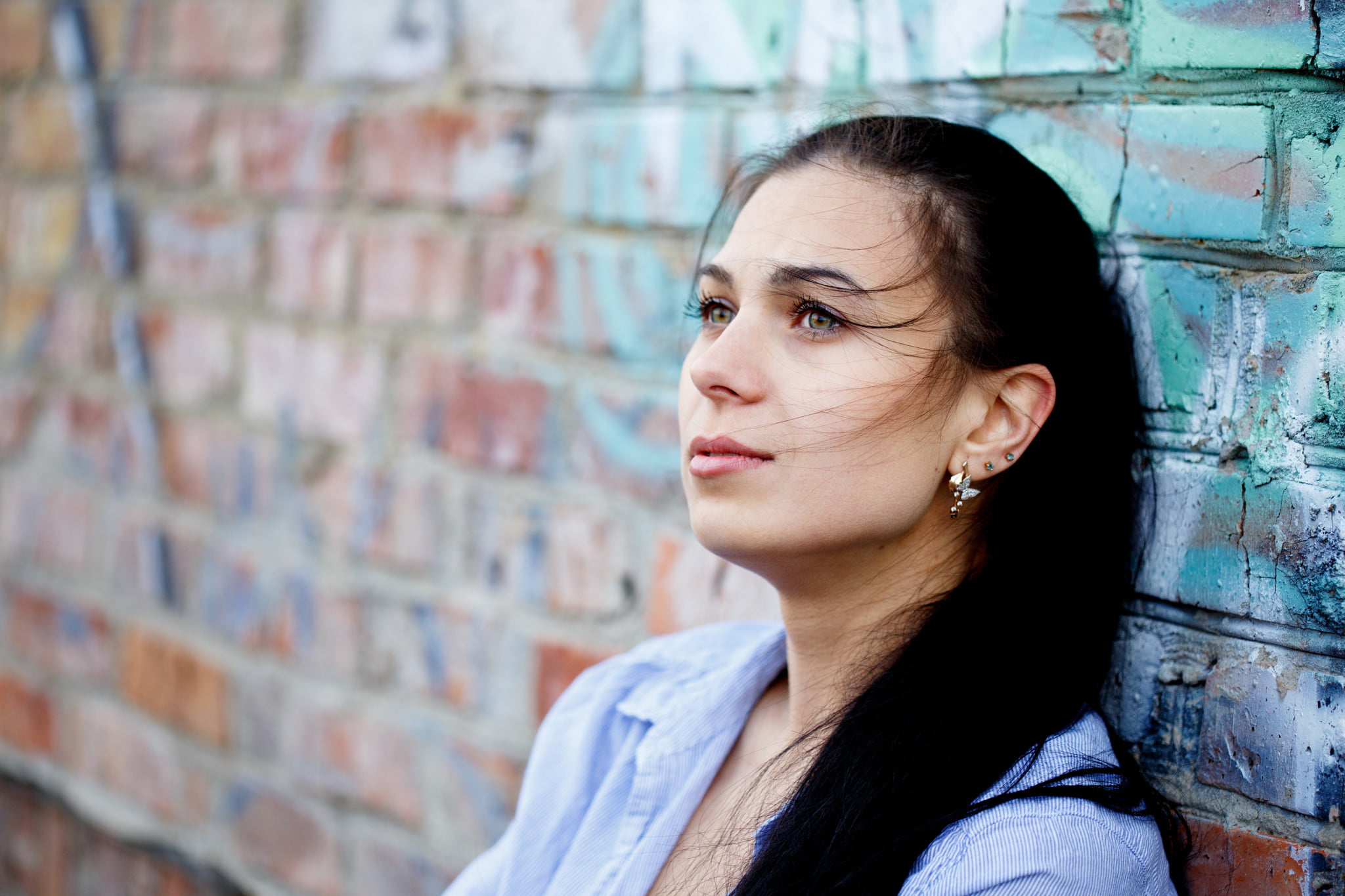 woman leans on brick wall