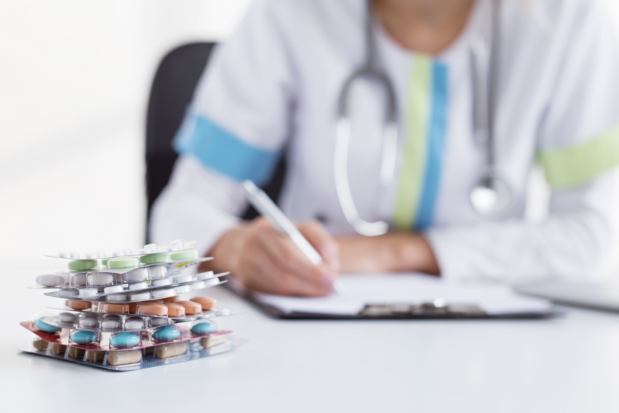 non-dispensing pharmacists: pharmacist sitting behind desk with pen and small pile of meds
