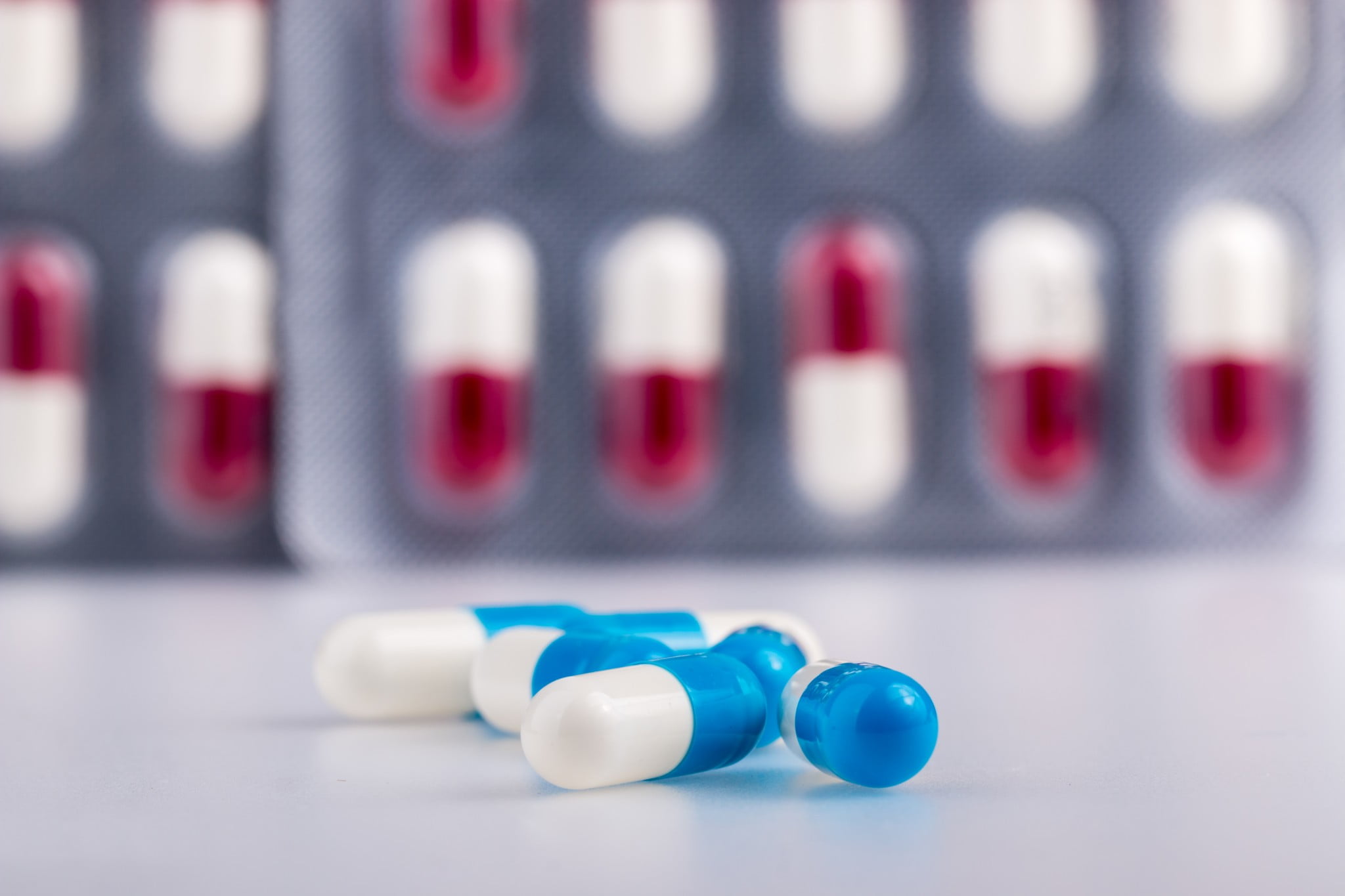 red and white antibiotics in blister pack with blue and white antibiotics loose in front