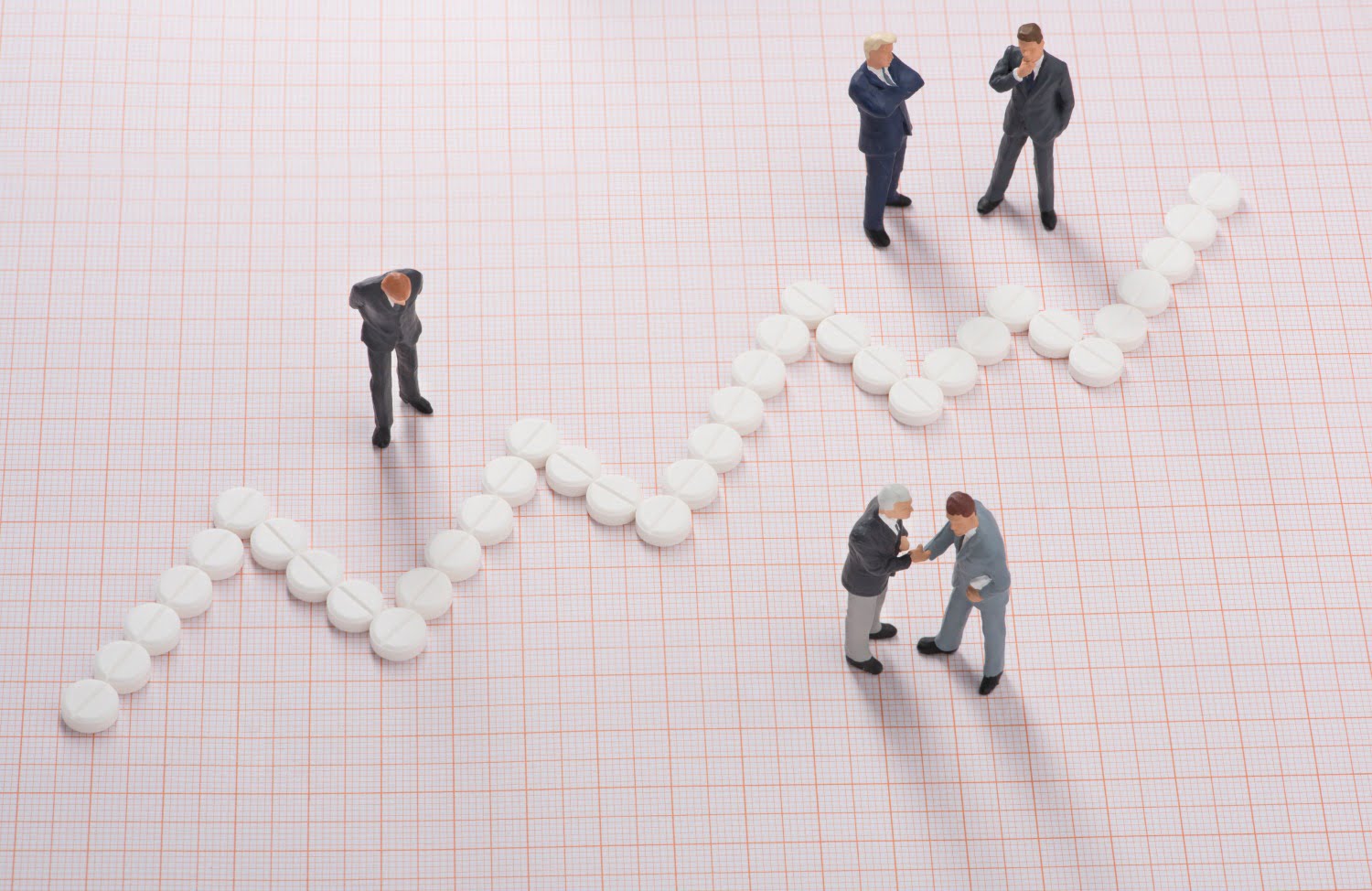 pharmacists standing by upward graph made of pills