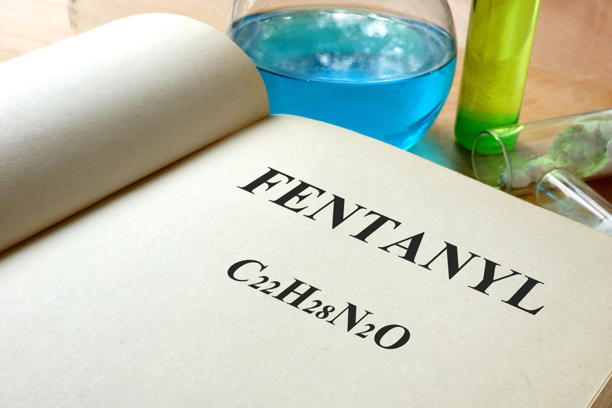 44171081 - book with fentanyl and test tubes on a table.