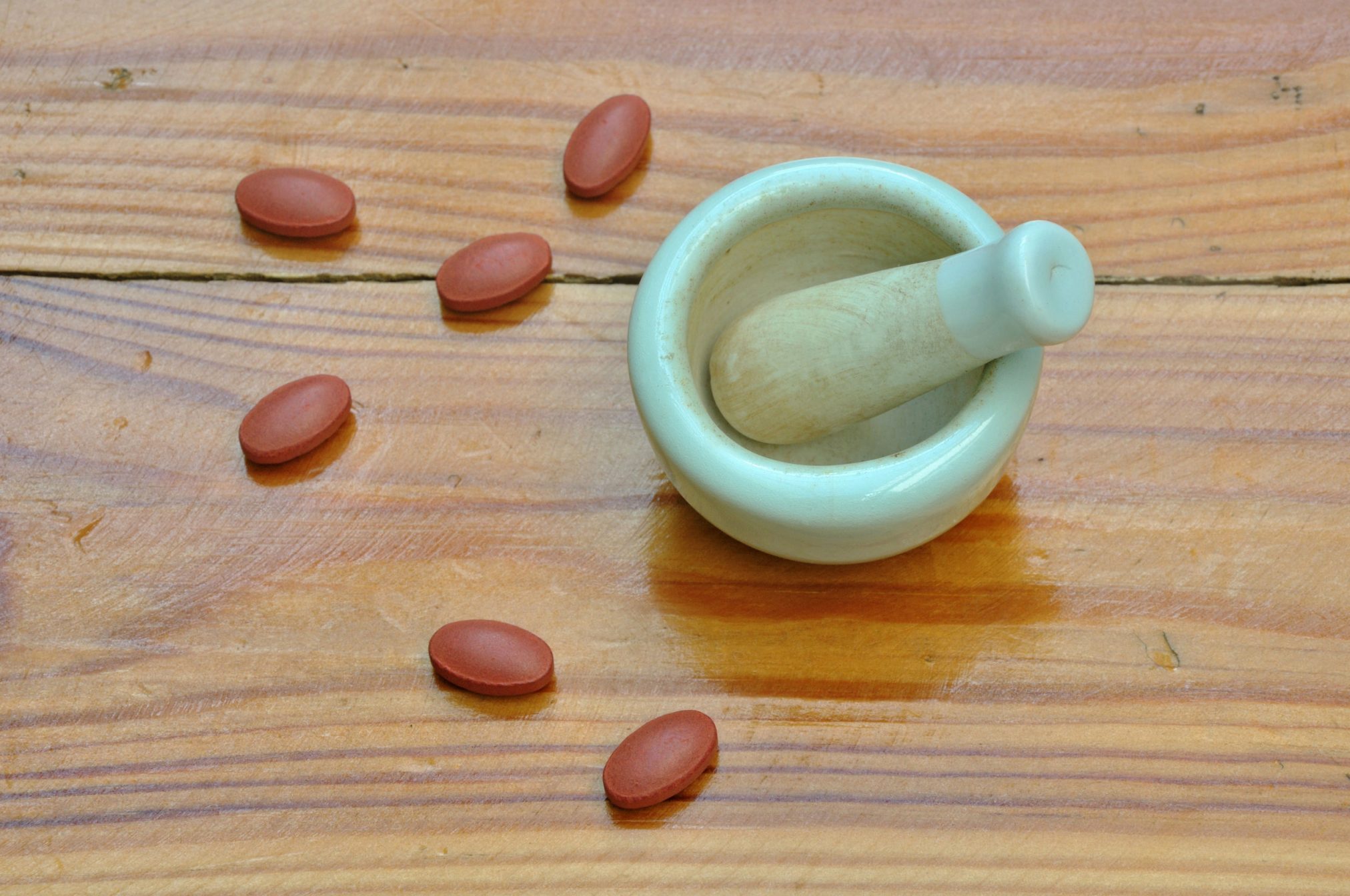 34744541 - a pestle and mortar with big drugs around on a wooden surface