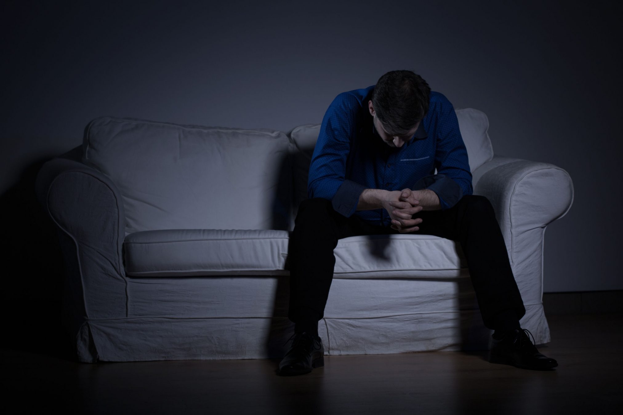 sad man on couch in dark