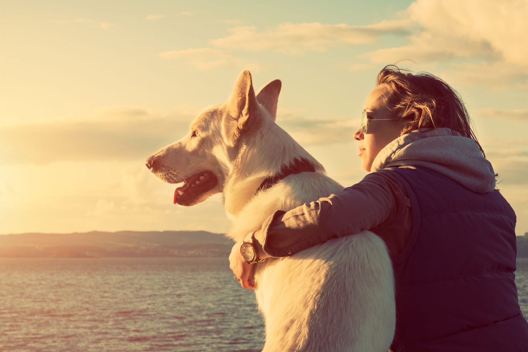 woman with dog looking pensive at beach