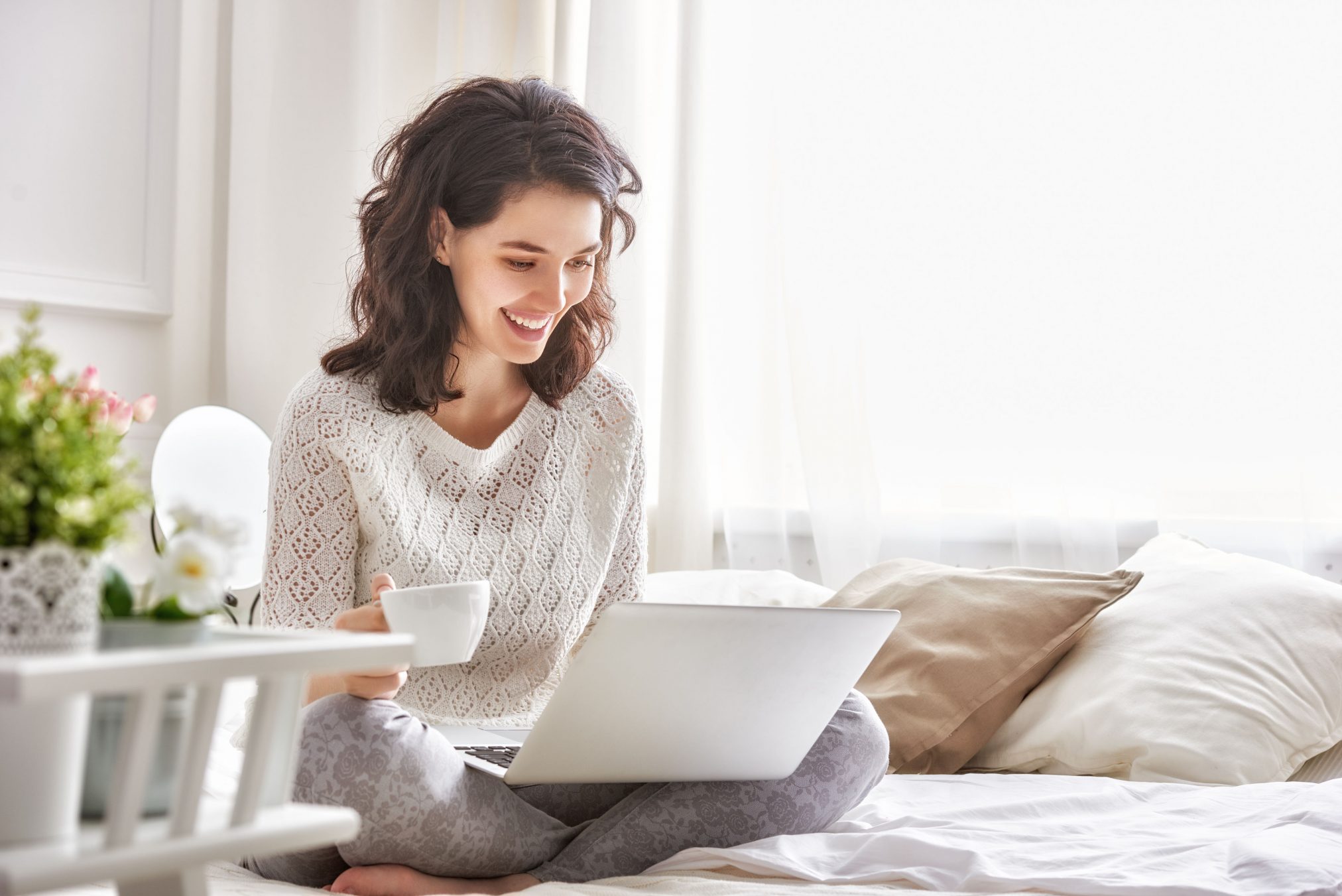 young woman reading laptop on bed