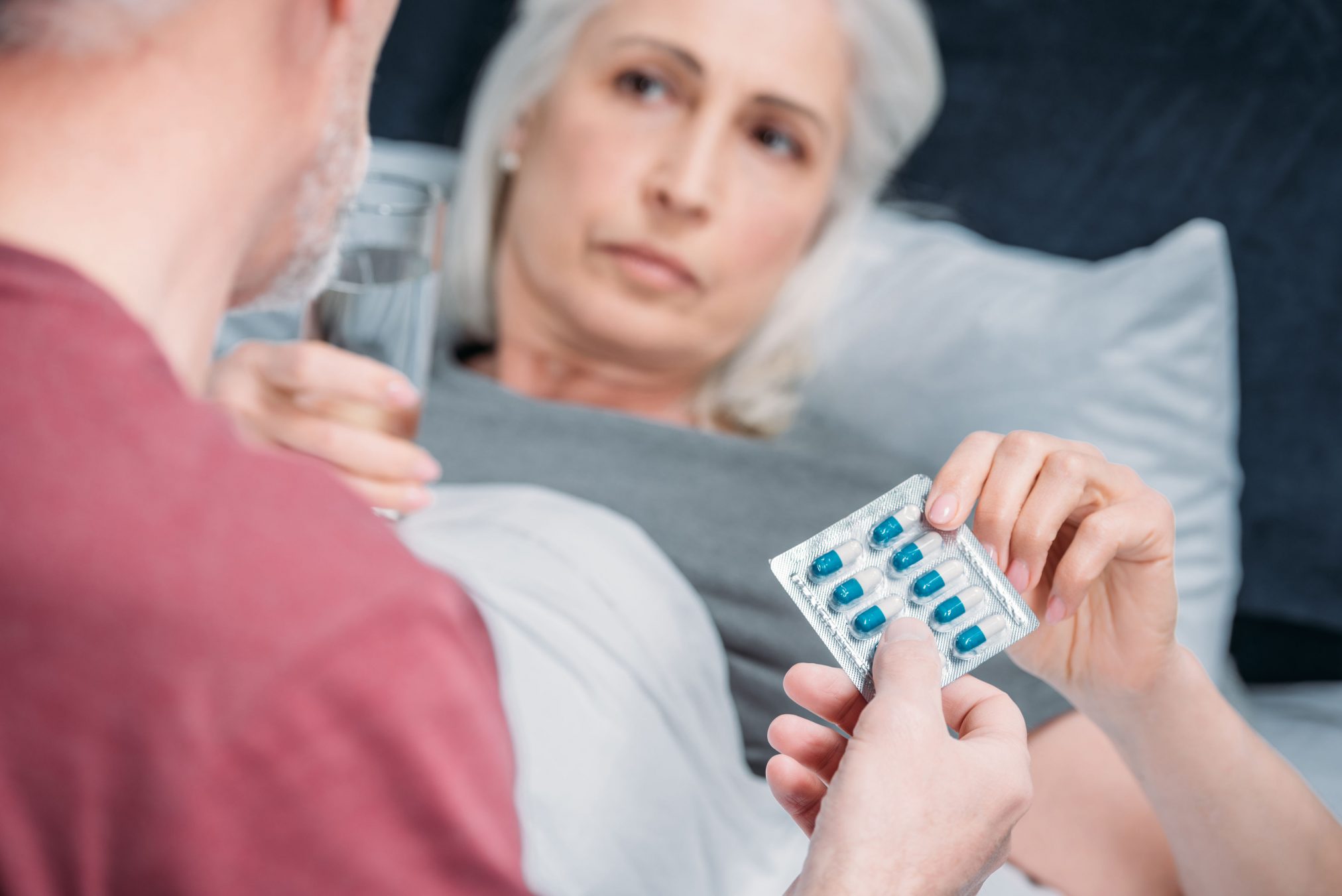 woman being handed pills by her husband