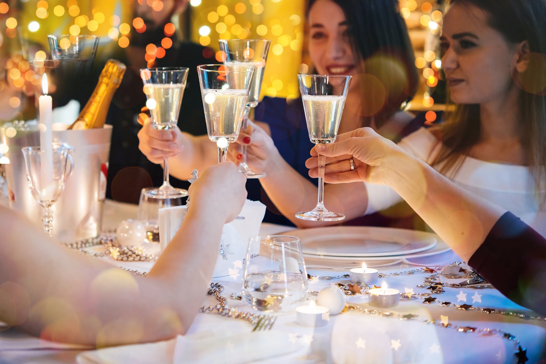 Friends celebrating Christmas or New Year eve. Party table with champagne.