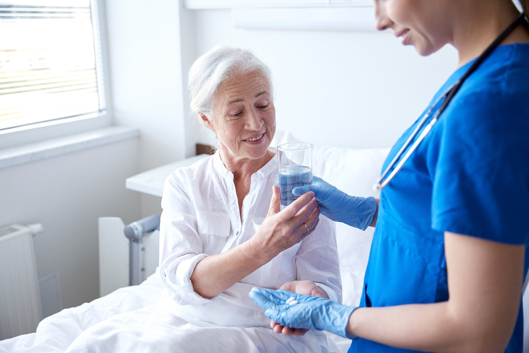 nurse giving medicine to senior elderly older woman at hospital nursing home