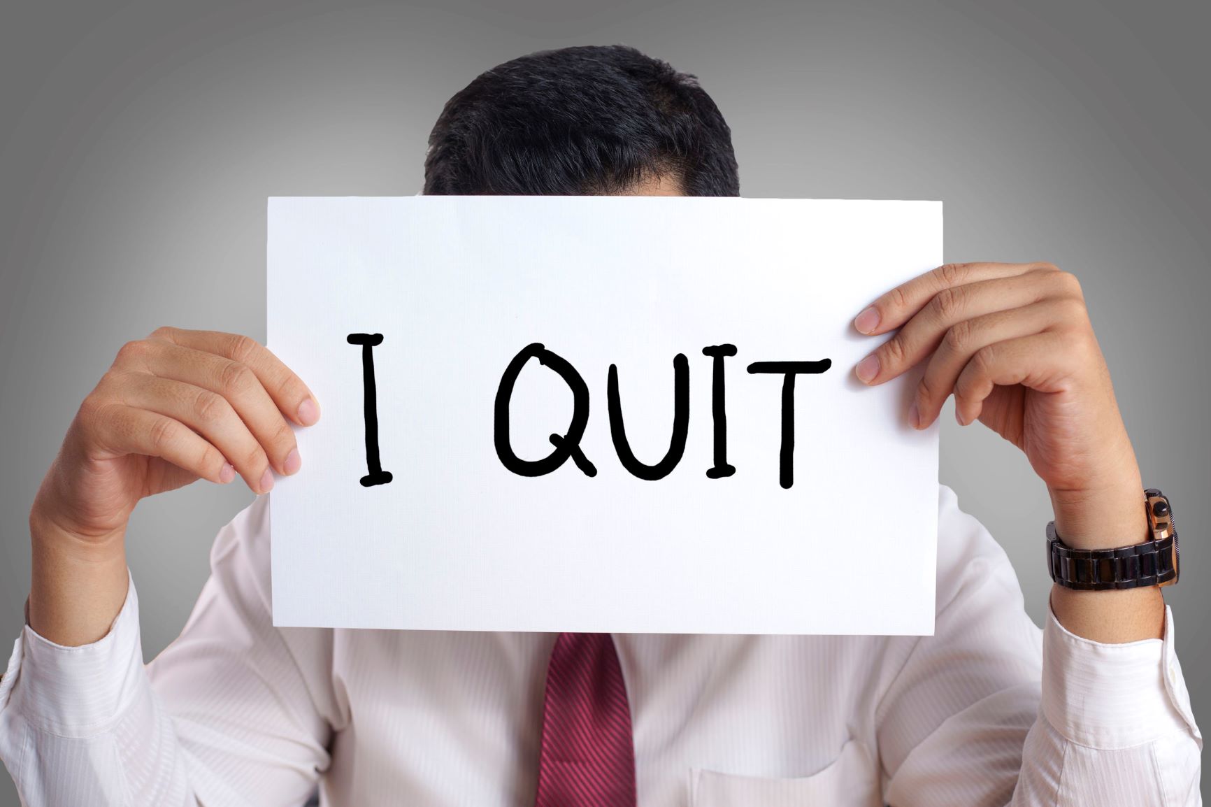 Businessman hiding his face behind paper with I quit words written on it